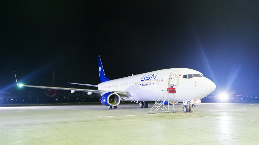 a white and blue airplane on a tarmac at night