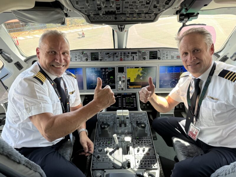two men in uniform sitting in a cockpit