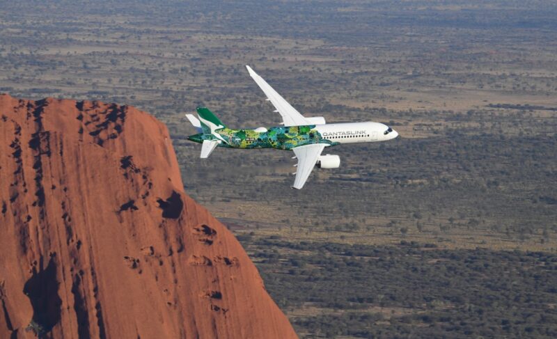 a plane flying over a red cliff