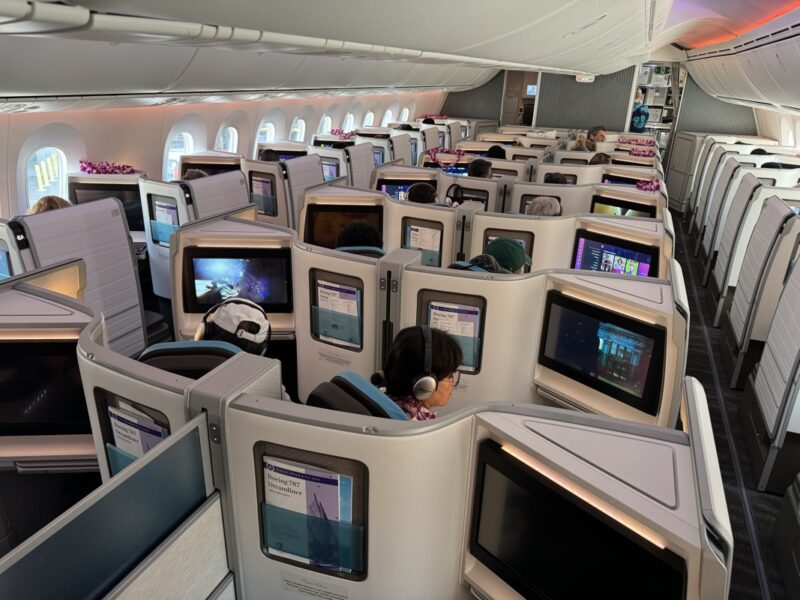 a group of people sitting in a row of monitors on an airplane