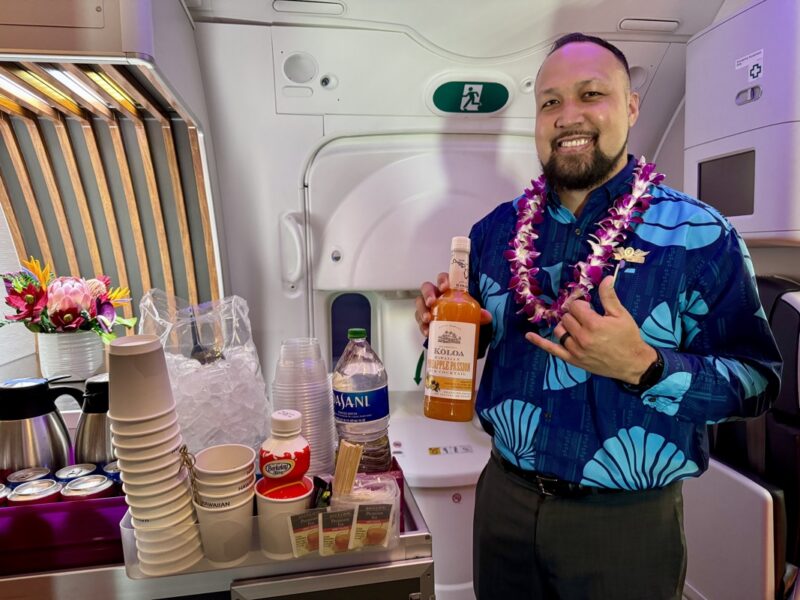 a man holding a bottle of alcohol in a plane