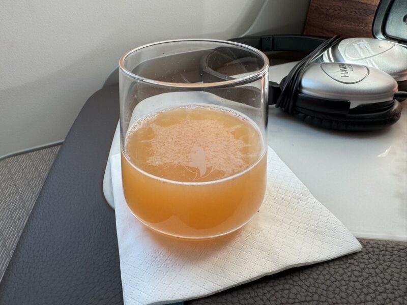 a glass of orange liquid on a napkin