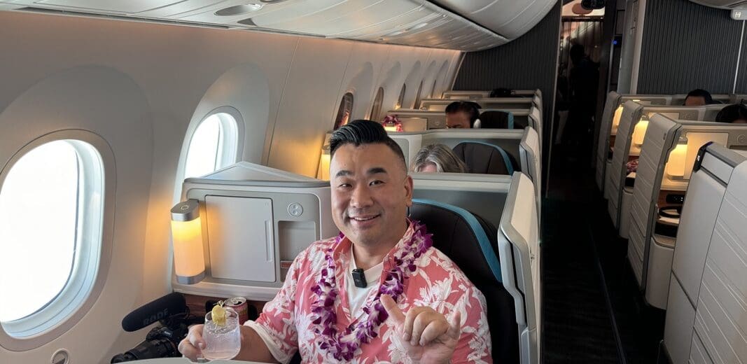 a man sitting in an airplane with a lei around his neck