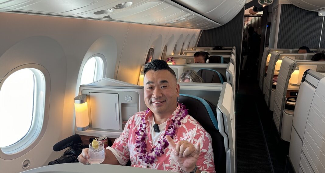 a man sitting in an airplane with a lei around his neck