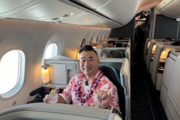 a man sitting in an airplane with a lei around his neck