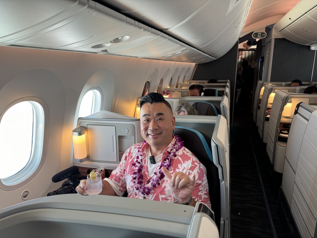 a man sitting in an airplane with a lei around his neck