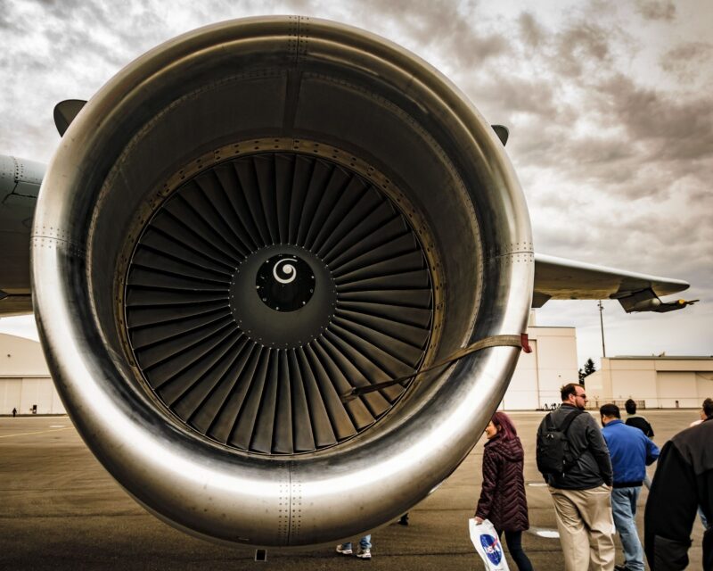 a group of people standing next to a jet engine
