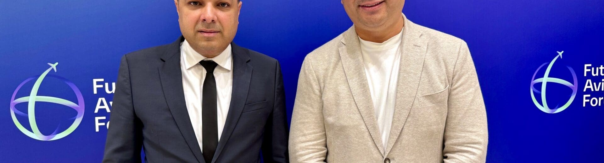 two men standing in front of a blue wall