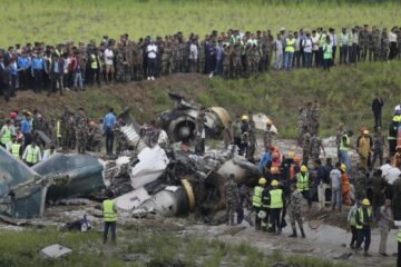 a group of people standing around a crashed plane