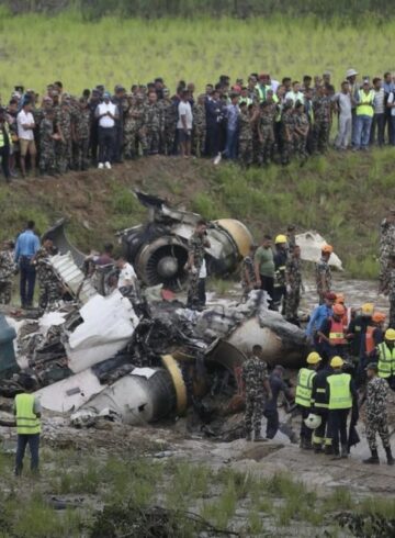 a group of people standing around a crashed plane