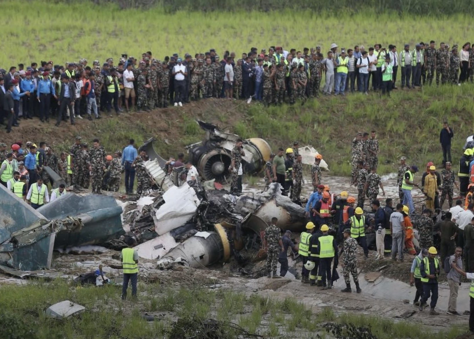 a group of people standing around a crashed plane