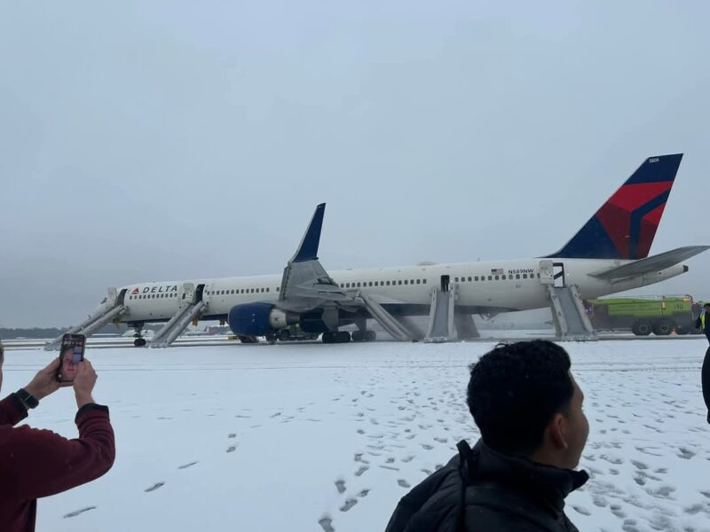 a plane on the ground with people in the snow