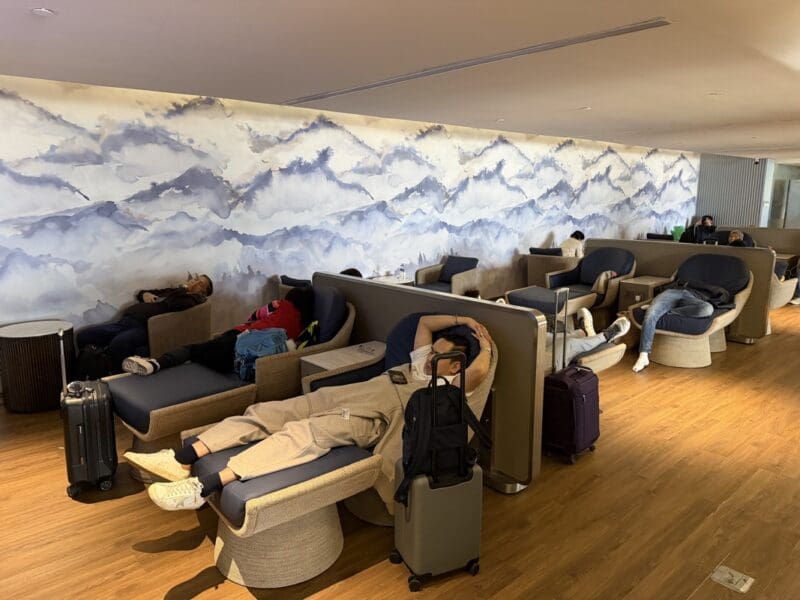 a group of people sitting in chairs in a room with luggage