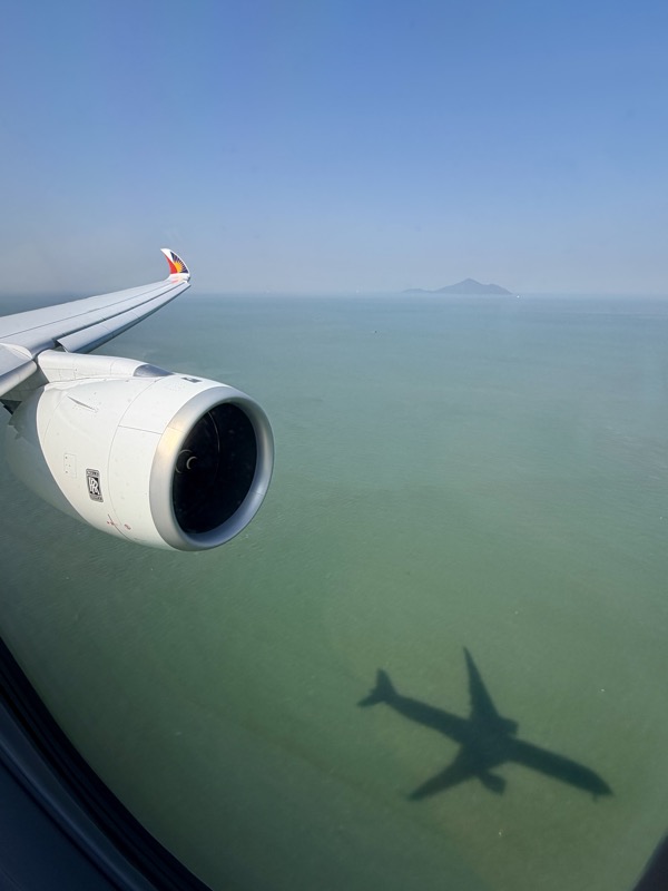 an airplane wing and shadow of an airplane on the water